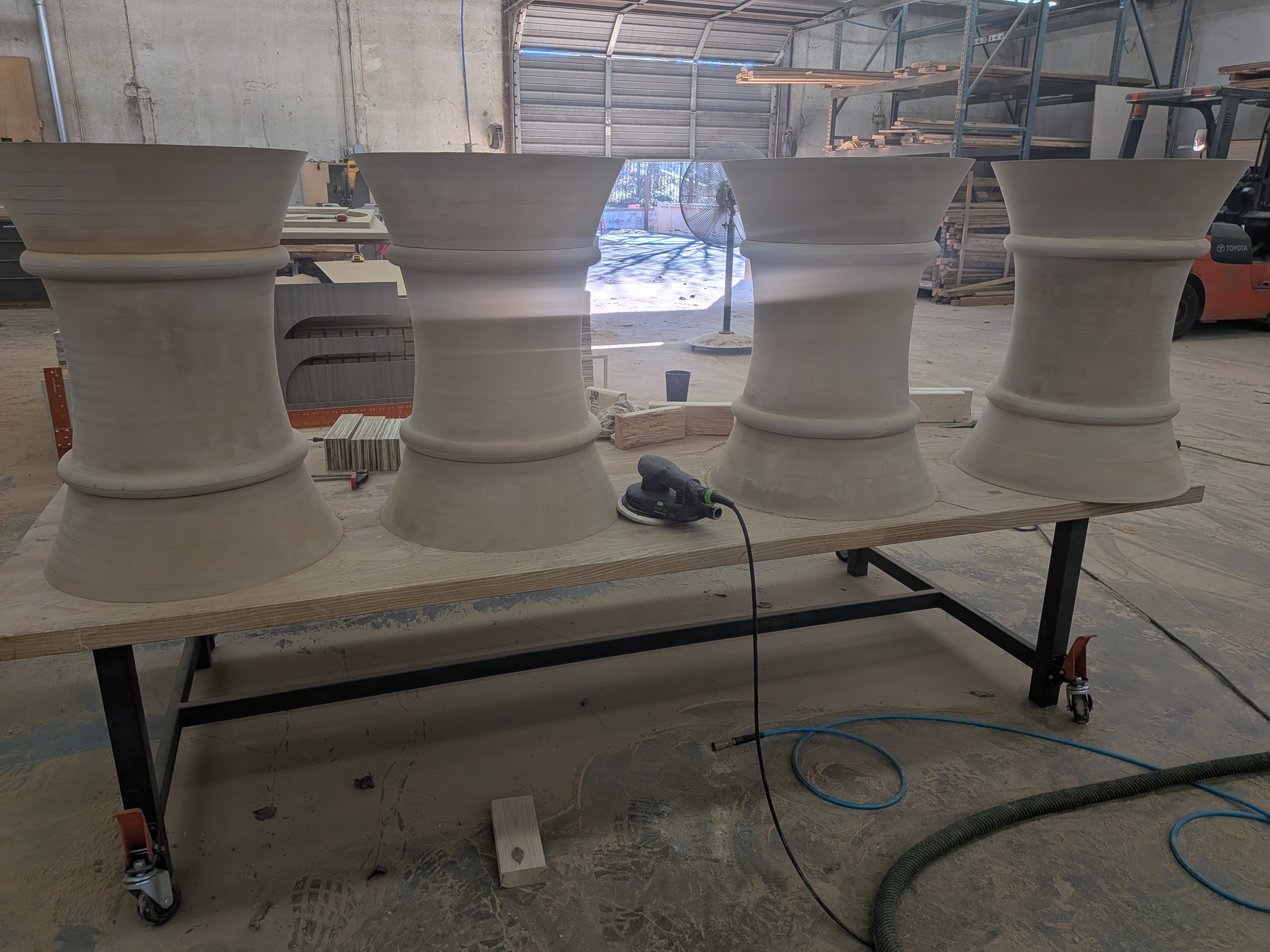 All four finished pedestal legs on a workbench before finishing