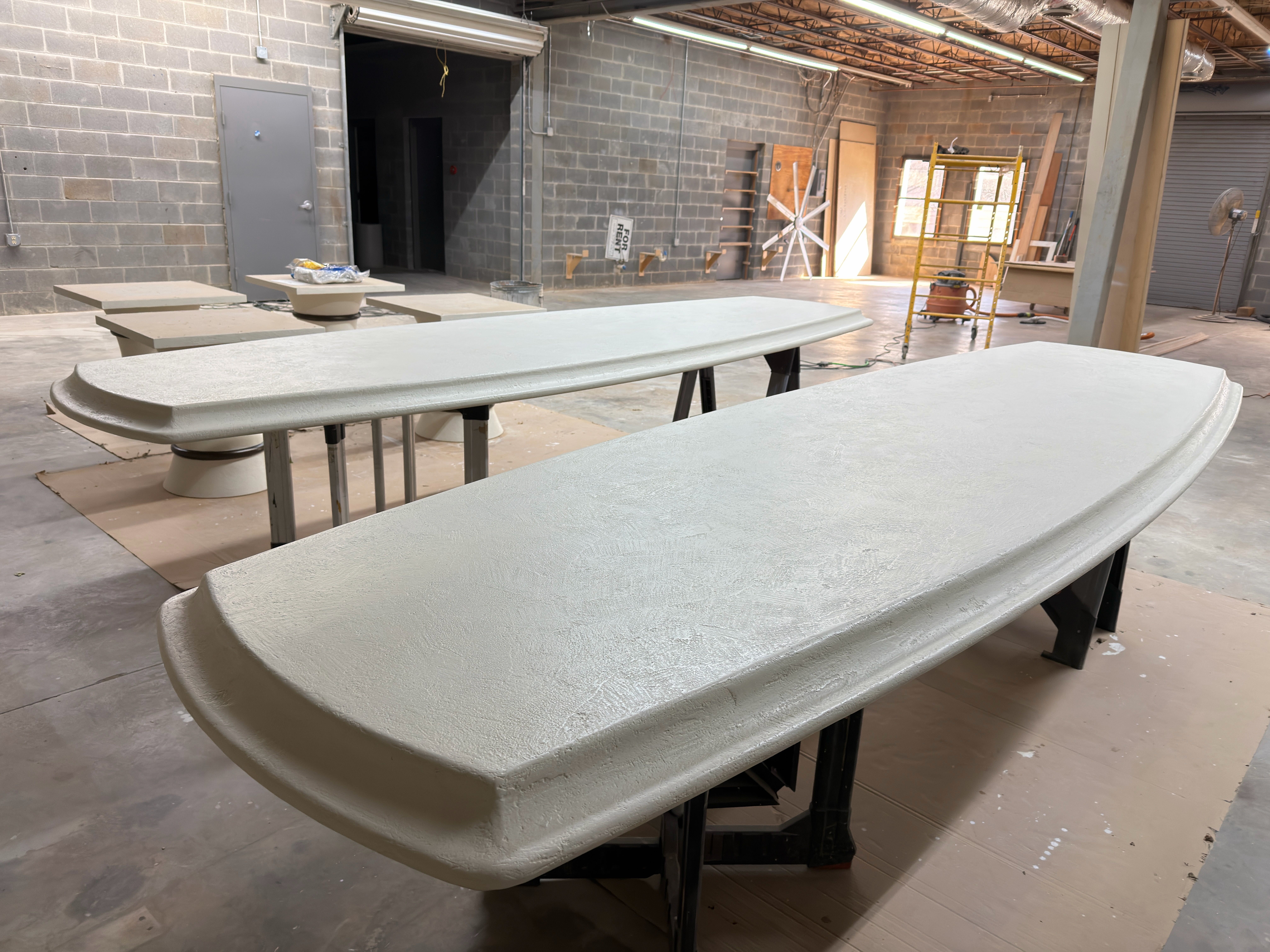Two table tops with plaster finish applied, staged in the shop