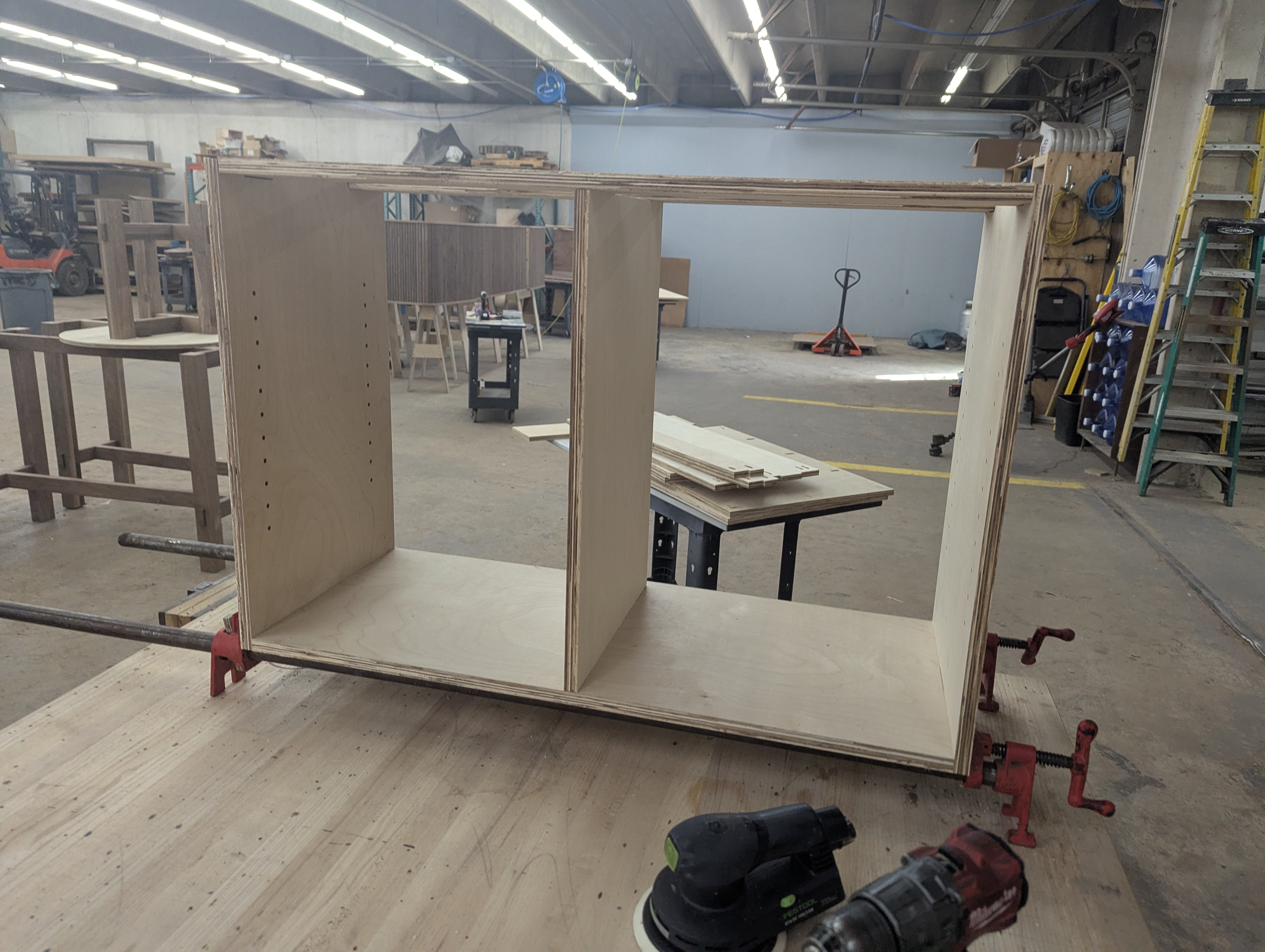 Full cabinet carcass assembled and clamped in the shop — two bays, adjustable shelf pin holes drilled