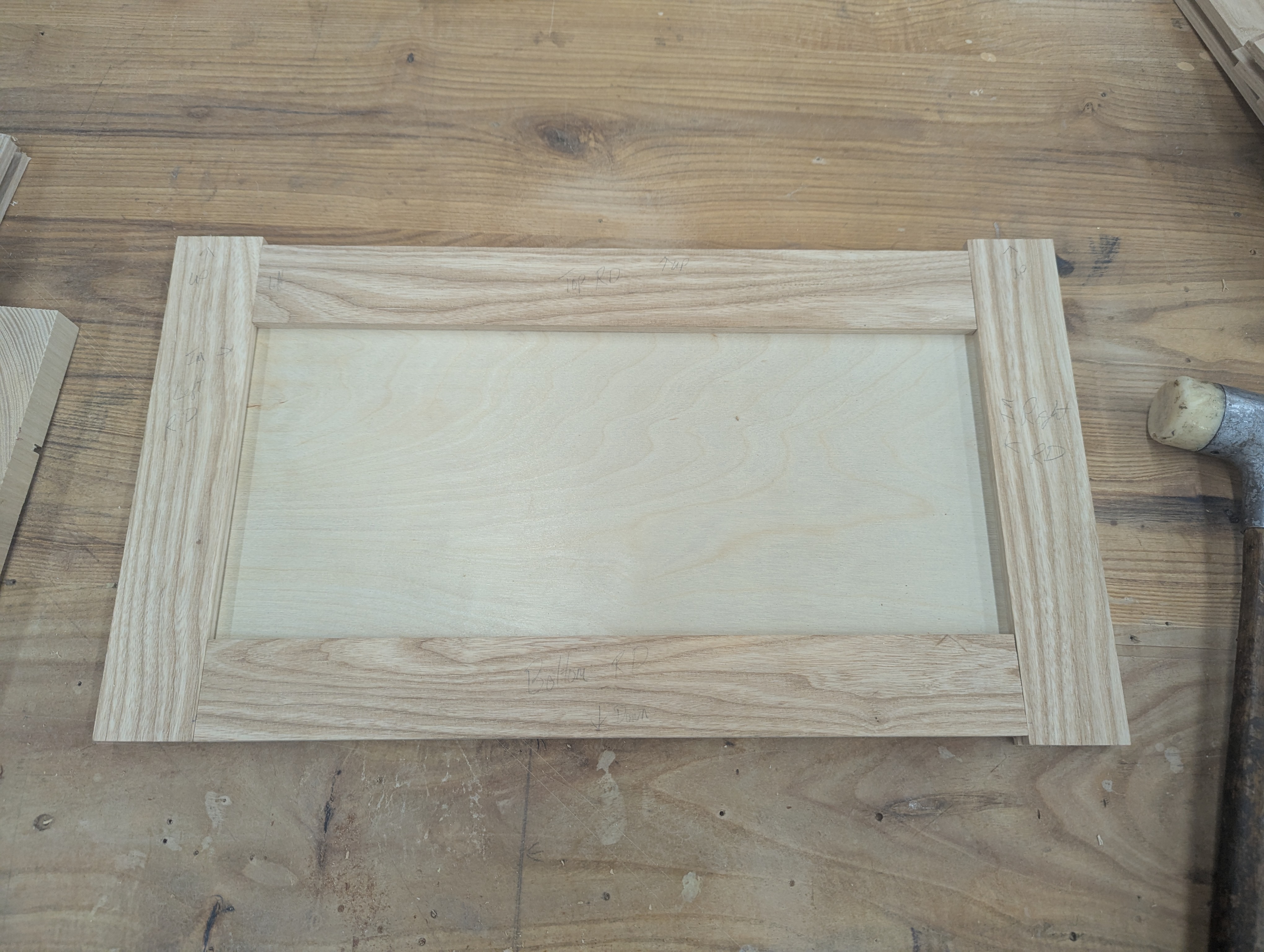 Shaker-style door face frame on the bench — ash stiles and rails with flat plywood center panel