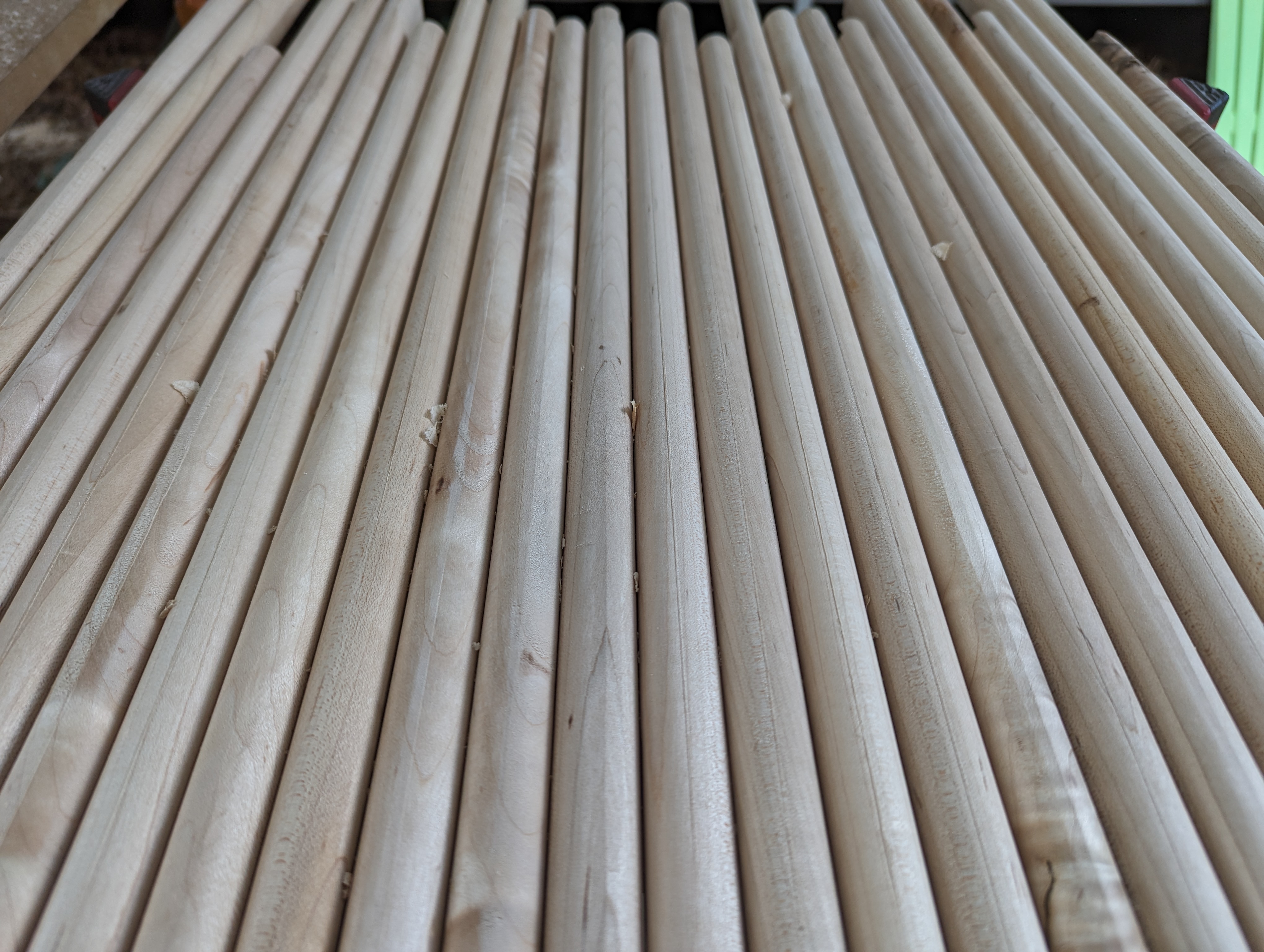 Rows of rounded wooden dowels laid out in the shop — the material that becomes the fluted sliding door panels