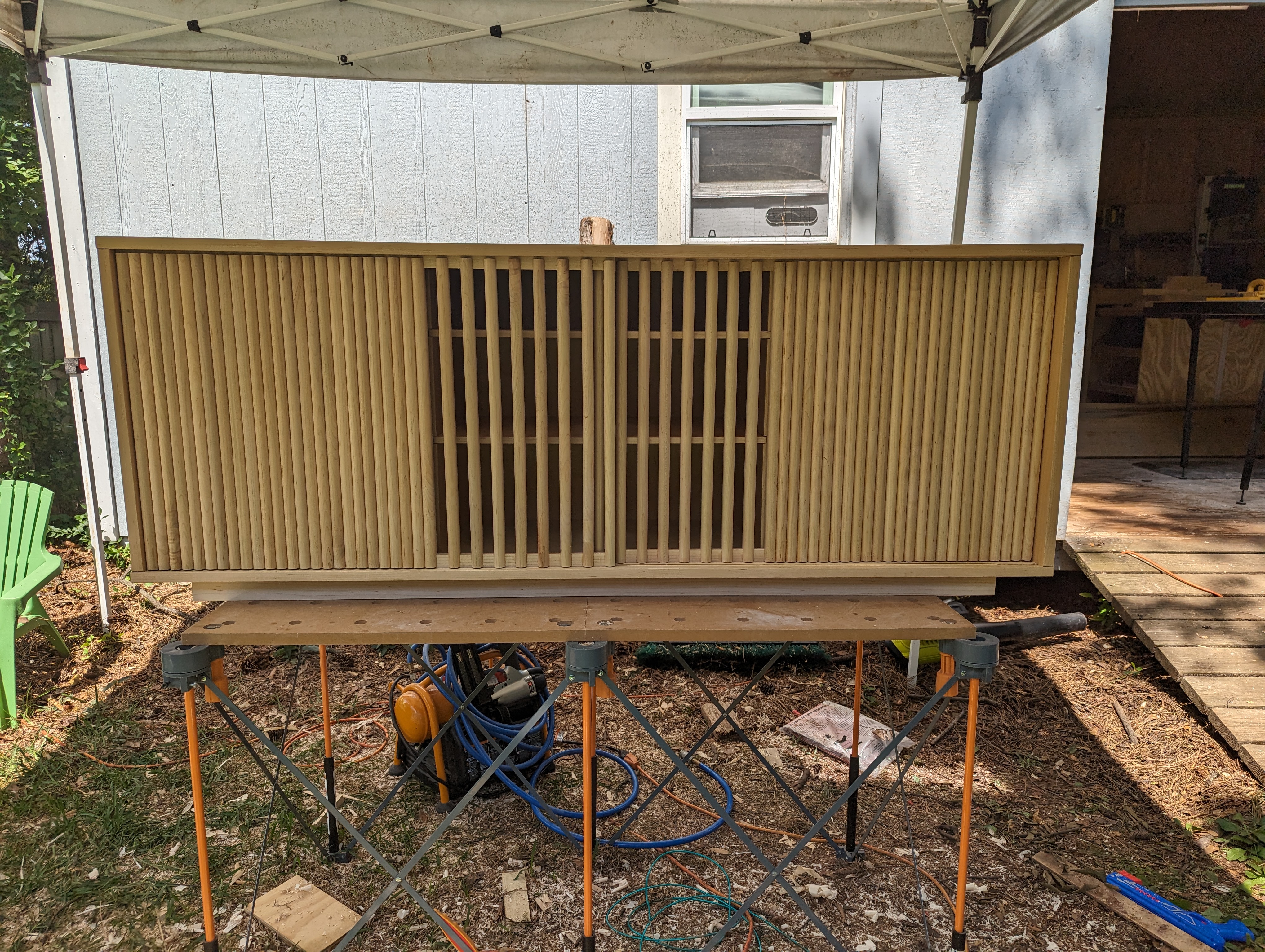 Console fully assembled outside before delivery — fluted sliding doors and lattice screen in place