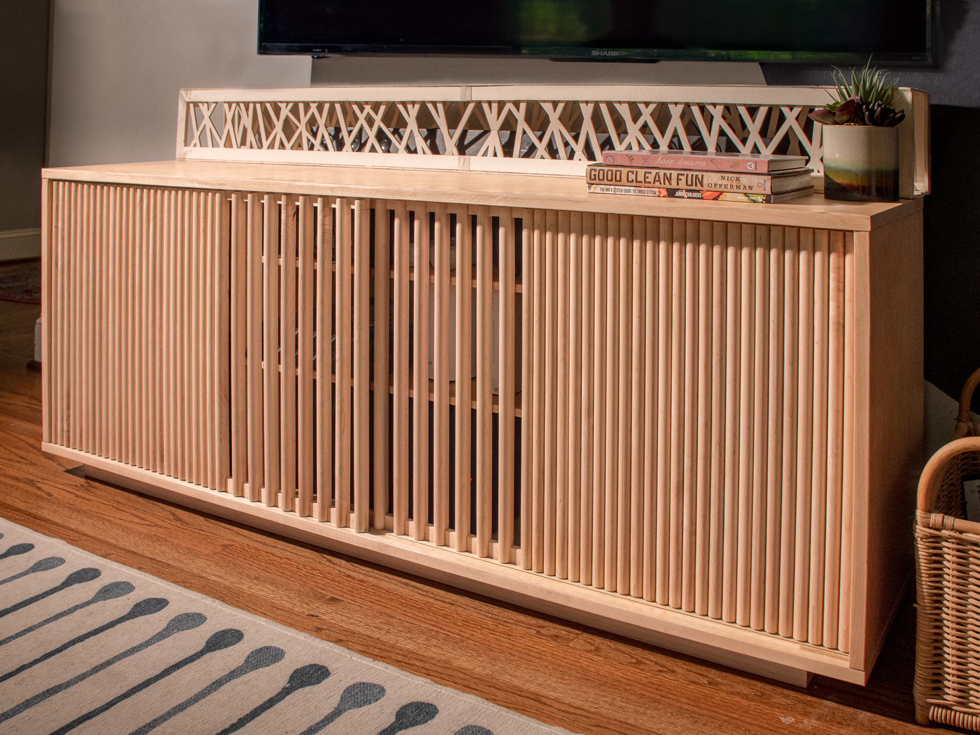 Three-quarter view of the console in the room — fluted doors closed, lattice screen and TV above